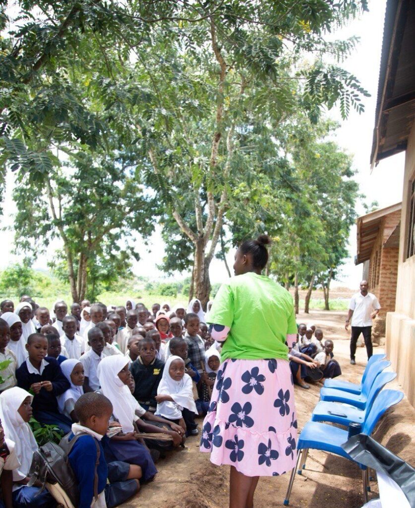 Group of young primary school students seated outdoors during a community advocacy session